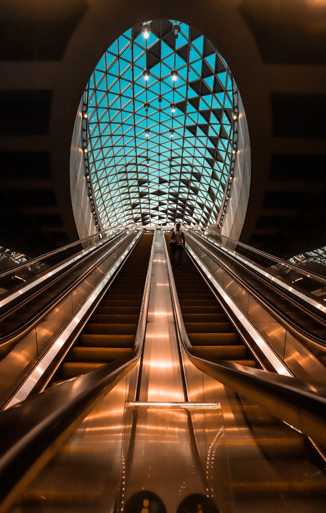 Stunning low-angle view of a modern escalator and geometric ceiling design indoors.